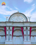 FRP floral arch with pediment, red drapes and angel statues for a marriage garden